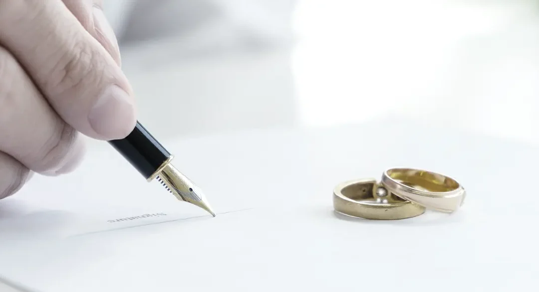 Divorcio amistoso. Abogado firmando un documento de divorcio con los anillos en primer plano.