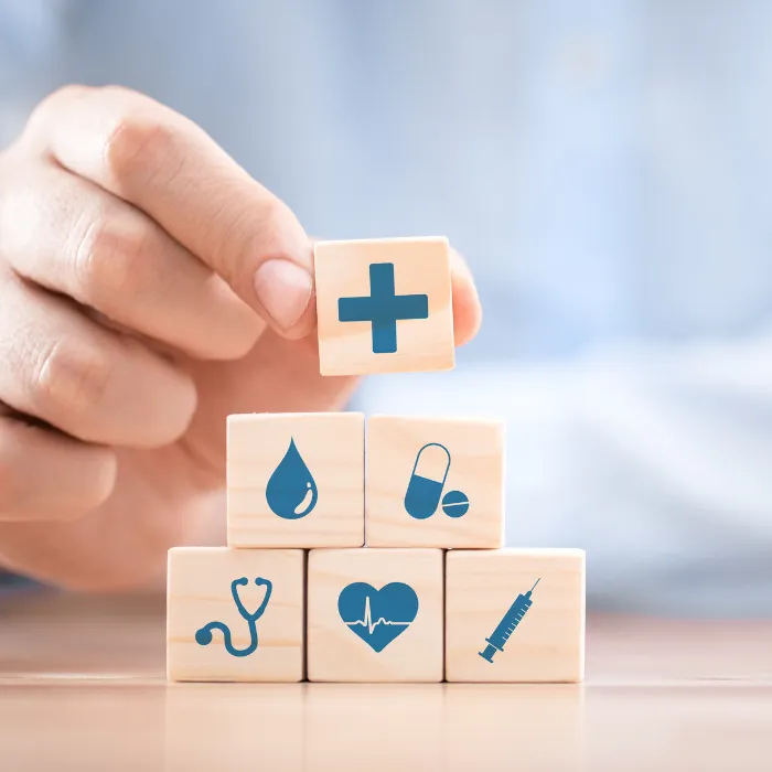 Persona colocando varios bloques con diferentes iconos relacionados con la salud
