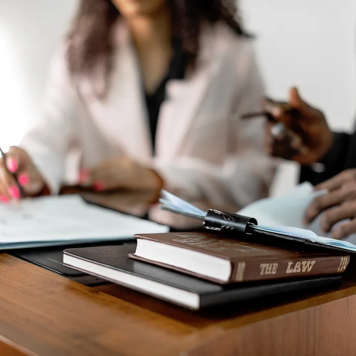Dos personas reunidas con varios libros de leyes